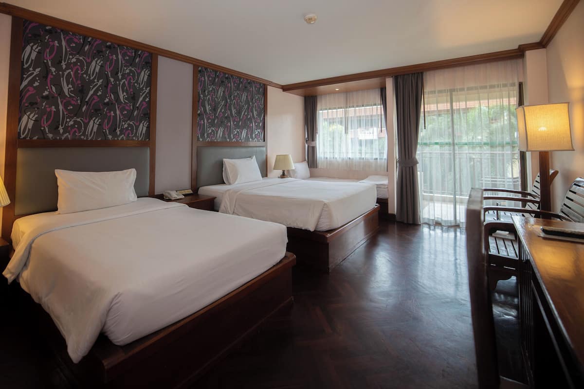 A hotel room with two beds, a desk, and a chair.