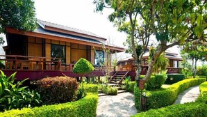 A traditional wooden building with a covered walkway and neatly trimmed hedges. - Baan Krating Pai Resort (Pai)