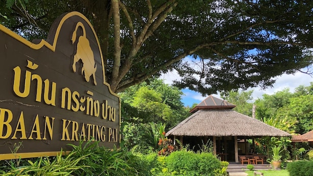 A sign for Baan Krating Pae with a thatched-roof structure in the background. - Baan Krating Pai Resort (Pai)