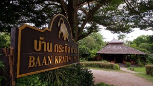 A sign for Baan Krating Pai with a thatched-roof structure in the background. - Baan Krating Pai Resort (Pai)
