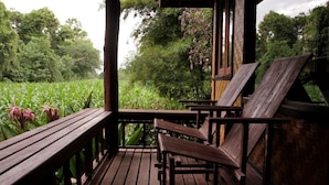 A wooden deck with benches overlooking a lush green field. - Baan Krating Pai Resort (Pai)