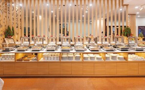 A buffet setup with multiple serving stations, a wooden decorative panel, and a tiled floor. - TTC Hotel - Da Lat (Xuan Huong - Da Lat)