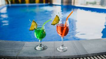 Two cocktails with garnishes on a poolside table.