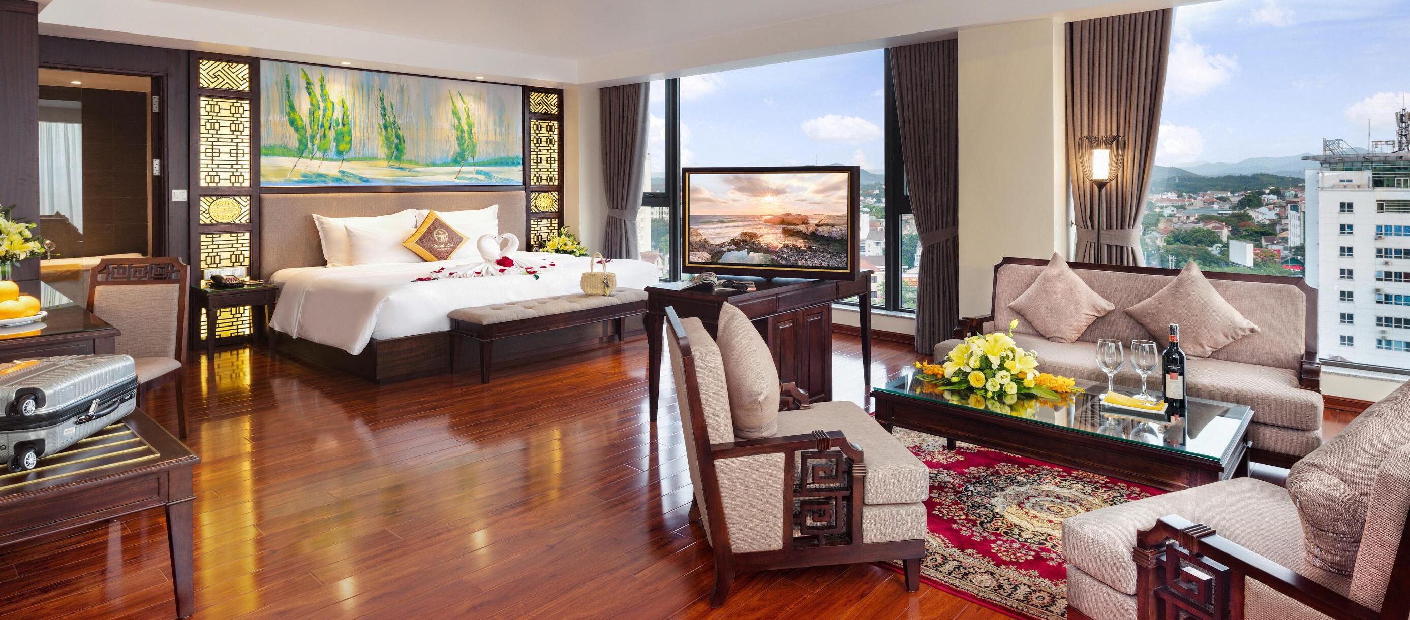 Una habitación de hotel con cama, sofá, mesa de centro y televisor.