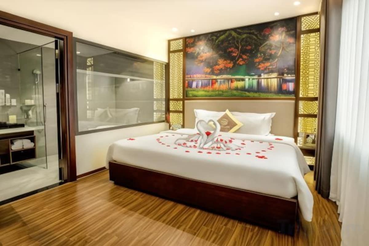 Una habitación de hotel con una cama grande, cabina de ducha de vidrio y un cuadro en la pared.