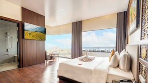 A hotel room with a large bed, a glass shower enclosure, a view of the city, and a painting on the wall. - Thanh Lich Royal Boutique Hotel (Hue)