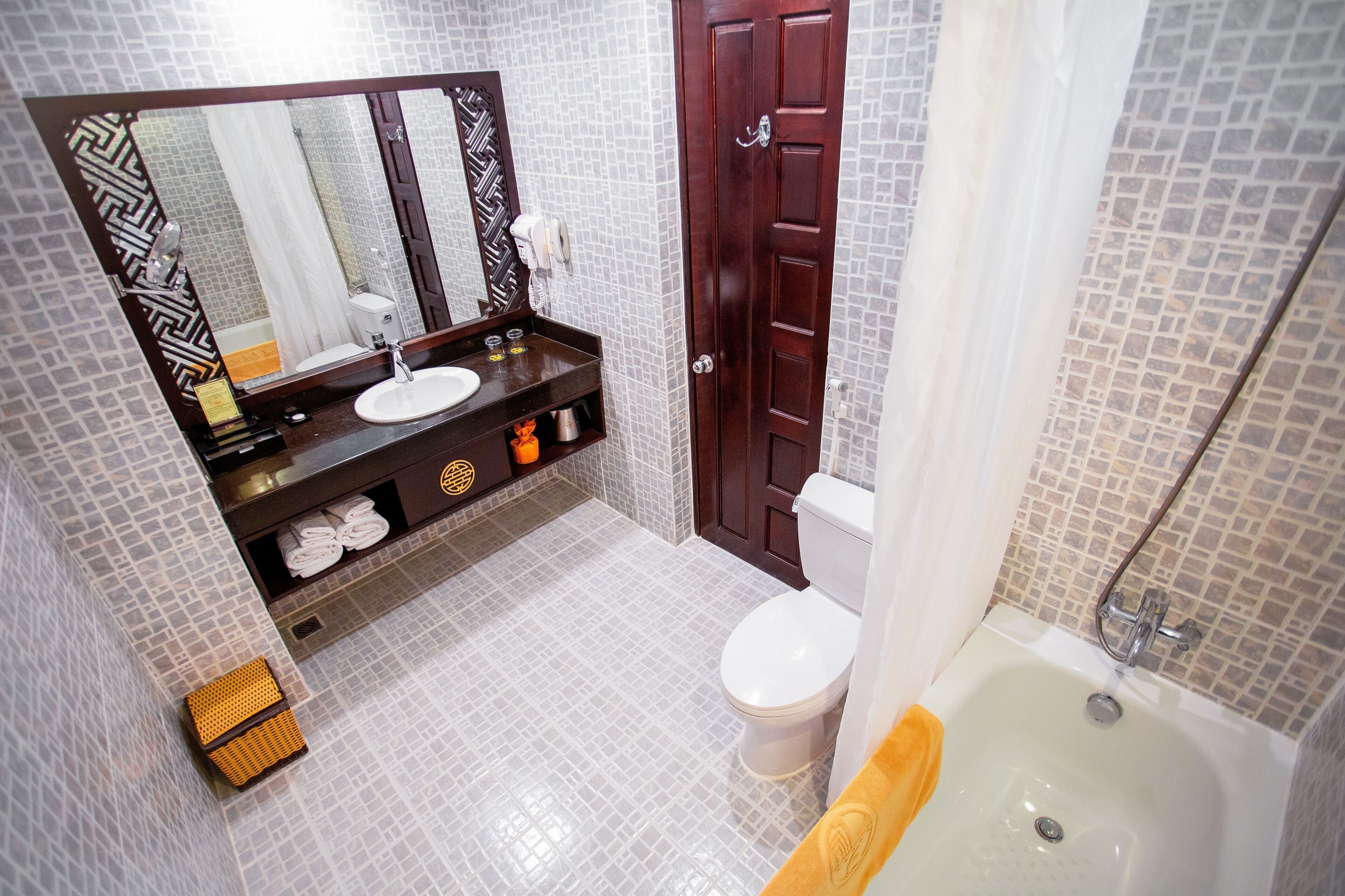 Un bagno con pavimento piastrellato, un lavabo con specchio, un WC e una vasca.