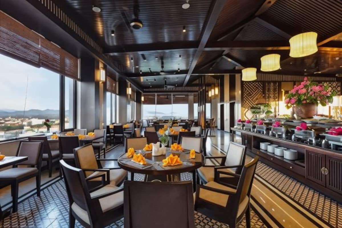 Un restaurante con mesas y sillas, una zona de bar y vistas a la ciudad.