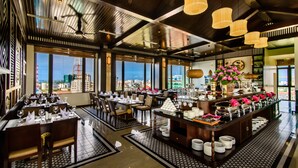 A modern restaurant with a high ceiling, large windows, and a buffet area. - Thanh Lich Royal Boutique Hotel (Hue)