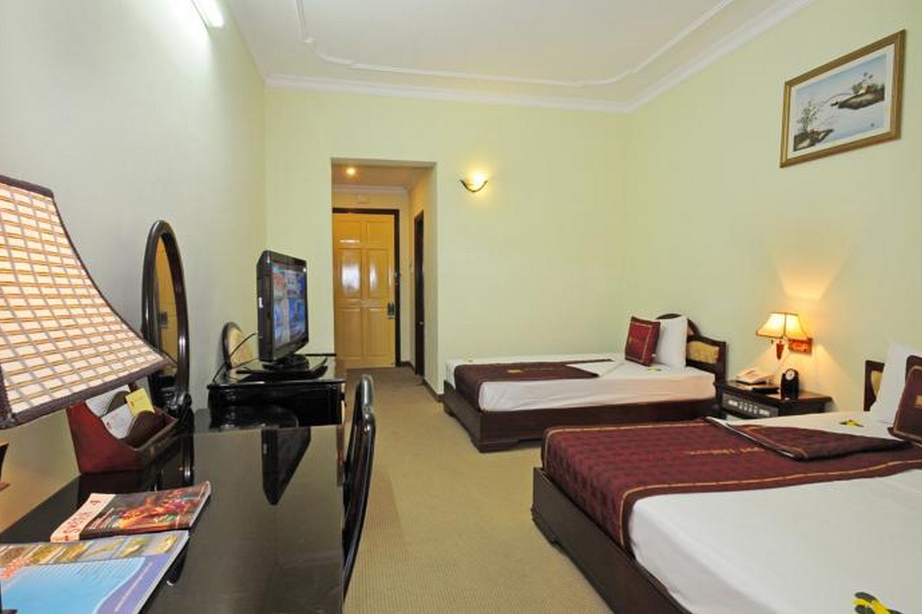 A hotel room with two beds, a desk with a computer, a lamp, and a television.
