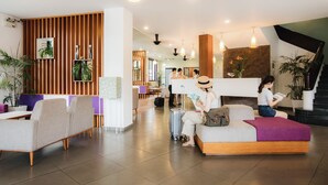 Eine moderne Lobby mit Sitzbereichen, einem Empfangstresen und einer Treppe.