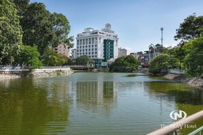 A river with a bridge, surrounded by trees and buildings. - The Tray Hotel Hai Phong (Hai Phong)