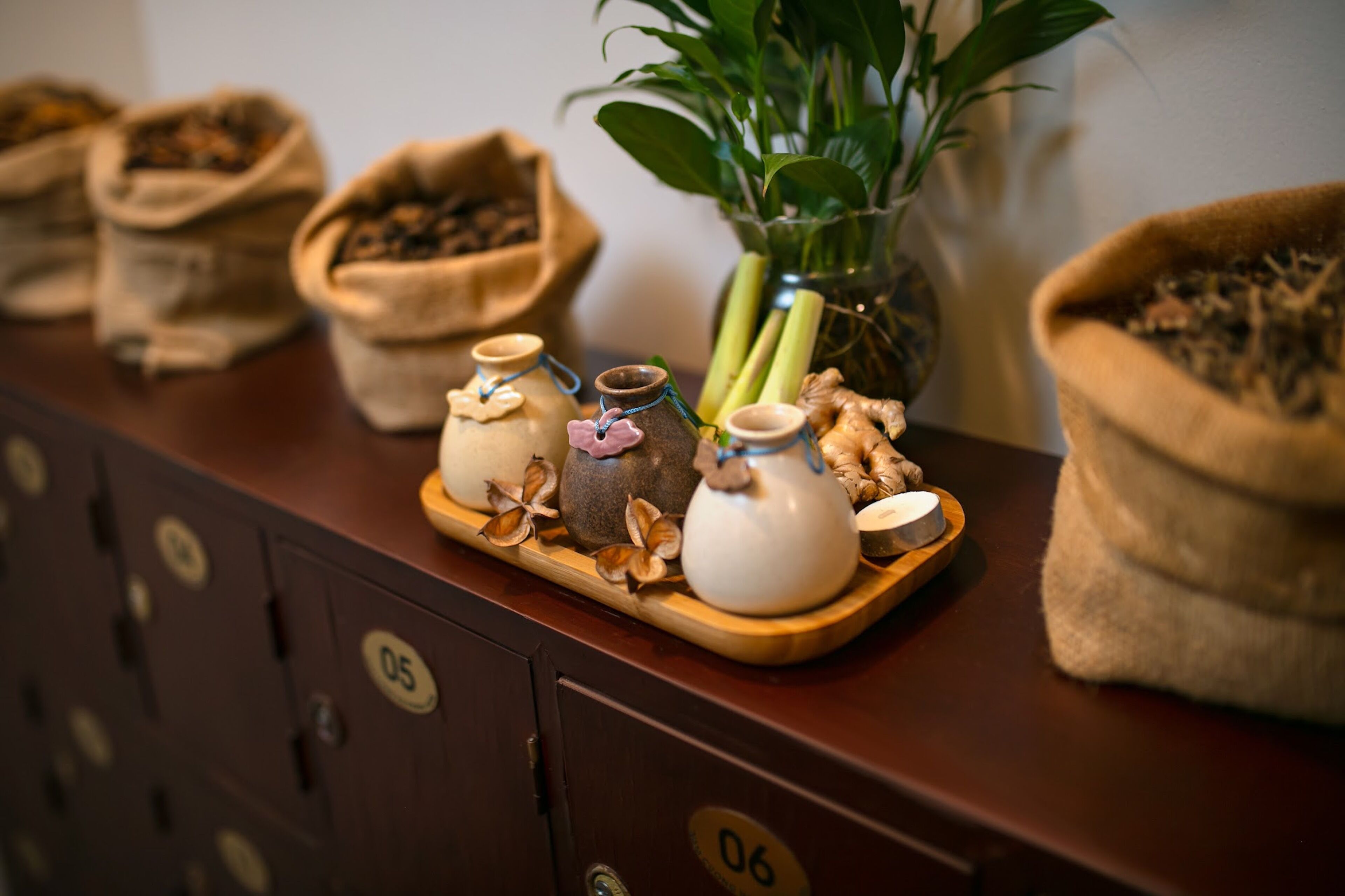 A wooden tray with jars and dried plants on a counter, next to a cabinet with numbered locks.