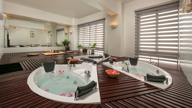 Ein moderner Wellnessraum mit einer großen, ovalen Badewanne, einer kleineren rechteckigen Badewanne und einer separaten Duschkabine.