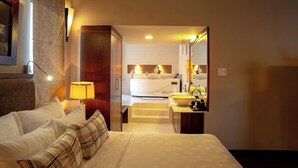 A hotel room with a bed, a bedside lamp, a bathroom with a sink and mirror, and a view of the bathroom through a doorway. - Asia Hotel Hue (Hue)