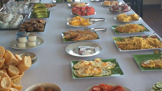 A buffet table with various food items including fruits, vegetables, and prepared dishes. - Thai Binh Hotel 2 (Hue)