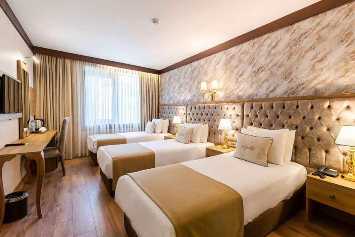 A hotel room with two beds, a desk, a chair, and a television.