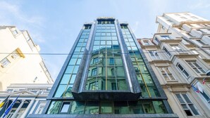 Ett högt hotell med en fasad av glas, en framträdande skylt med texten ”Marble” och klassiska arkitektoniska detaljer.
