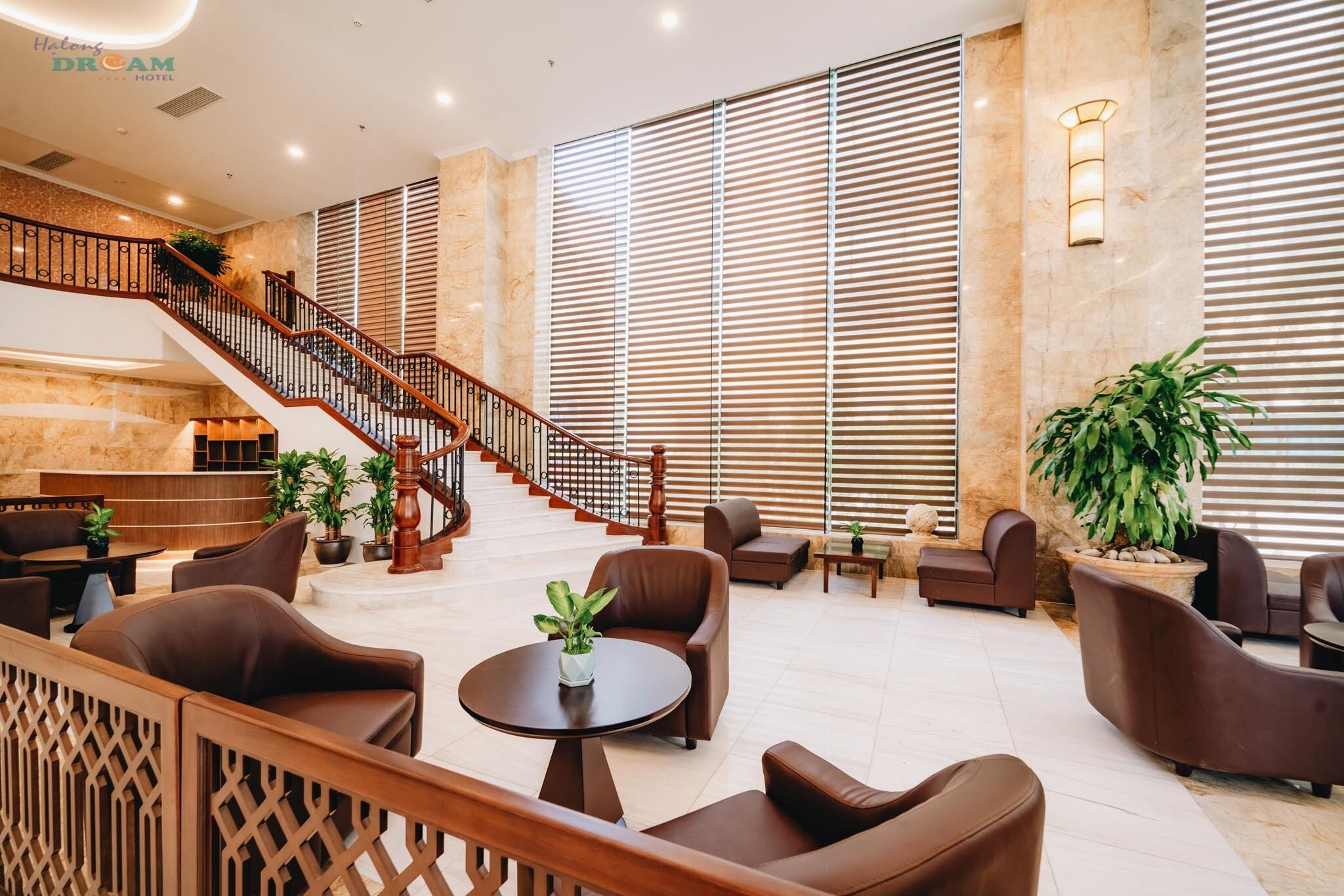 A spacious lobby with a staircase, seating area, and large windows.