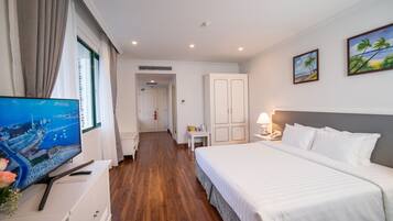 Een hotelkamer met een bed, een televisie, een bureau en uitzicht op de stad.