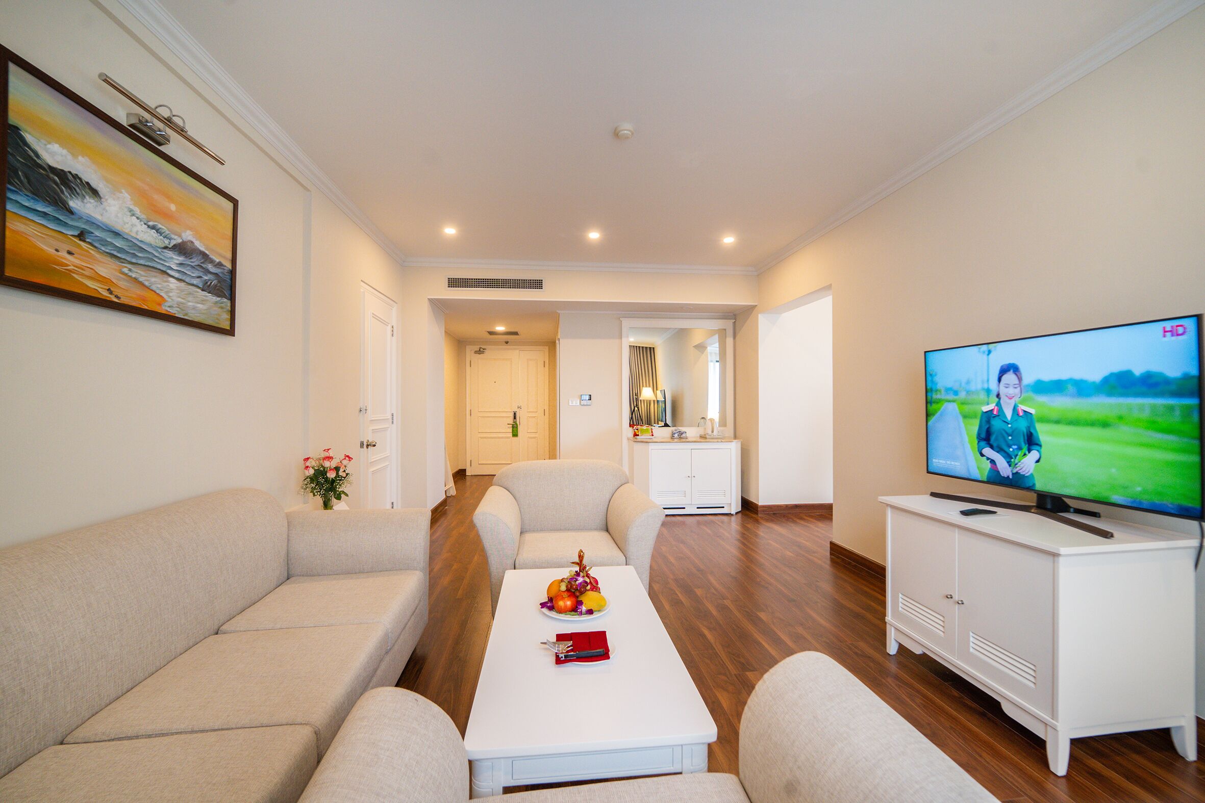 A modern living room with a sofa, a coffee table with a fruit bowl, a TV, and a white cabinet.