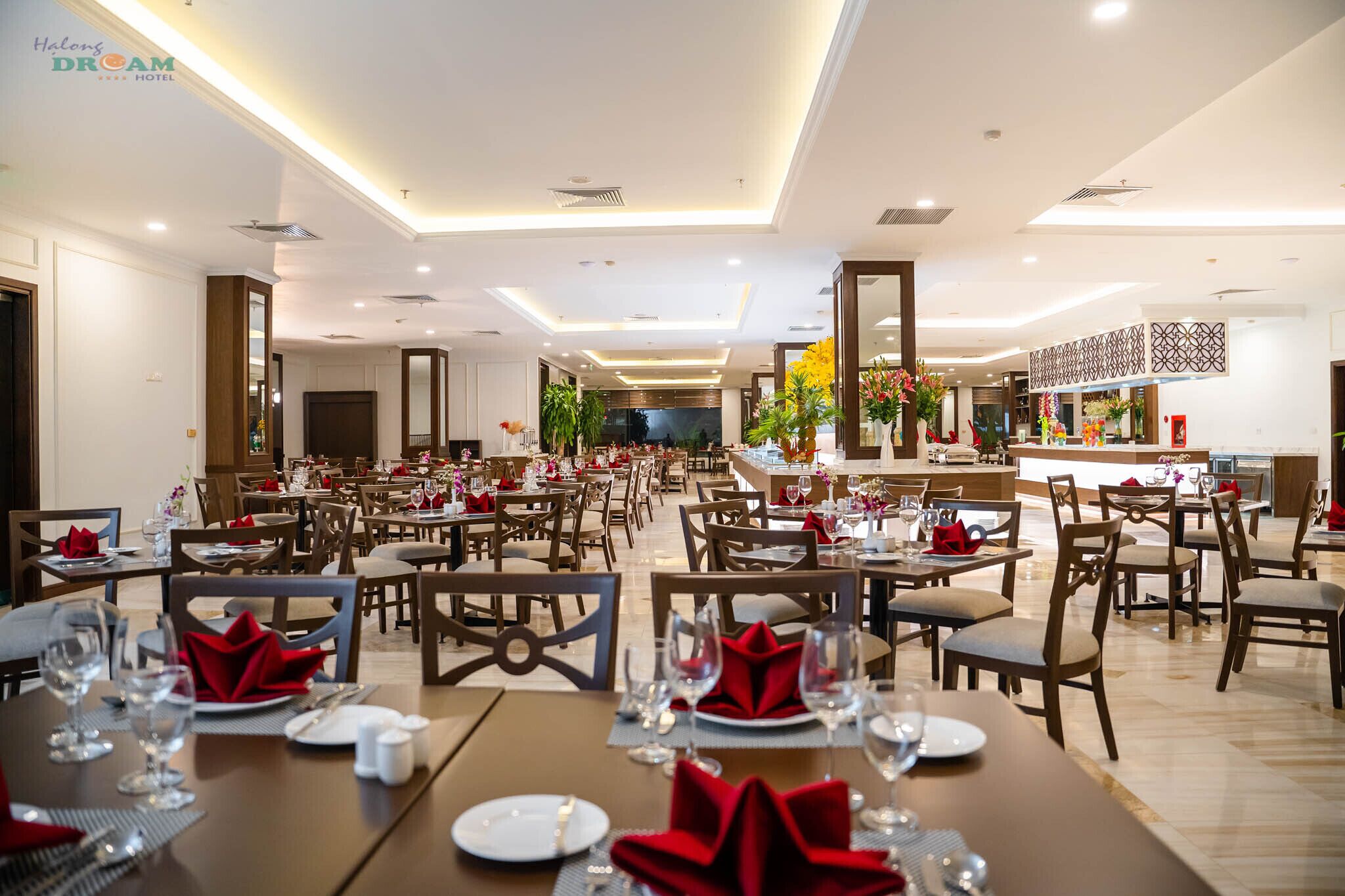 A spacious hotel dining area with multiple tables set for guests, featuring a modern ceiling design and a central bar area.