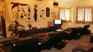 Ein Wohnzimmer mit Fernseher, Ledersofas, einem Couchtisch und einer Wand, die mit ägyptischen Hieroglyphen verziert ist.