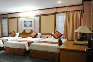 A hotel room with two single beds, a desk with a lamp, a framed picture on the wall, and a window with curtains. - Hanoi Heritage Hotel (Hanoi)