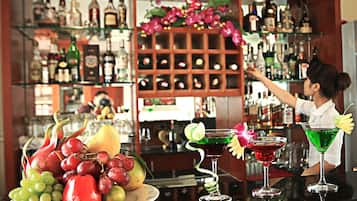 Un espace bar avec un barman, un présentoir de fruits et une variété de bouteilles et de verres.