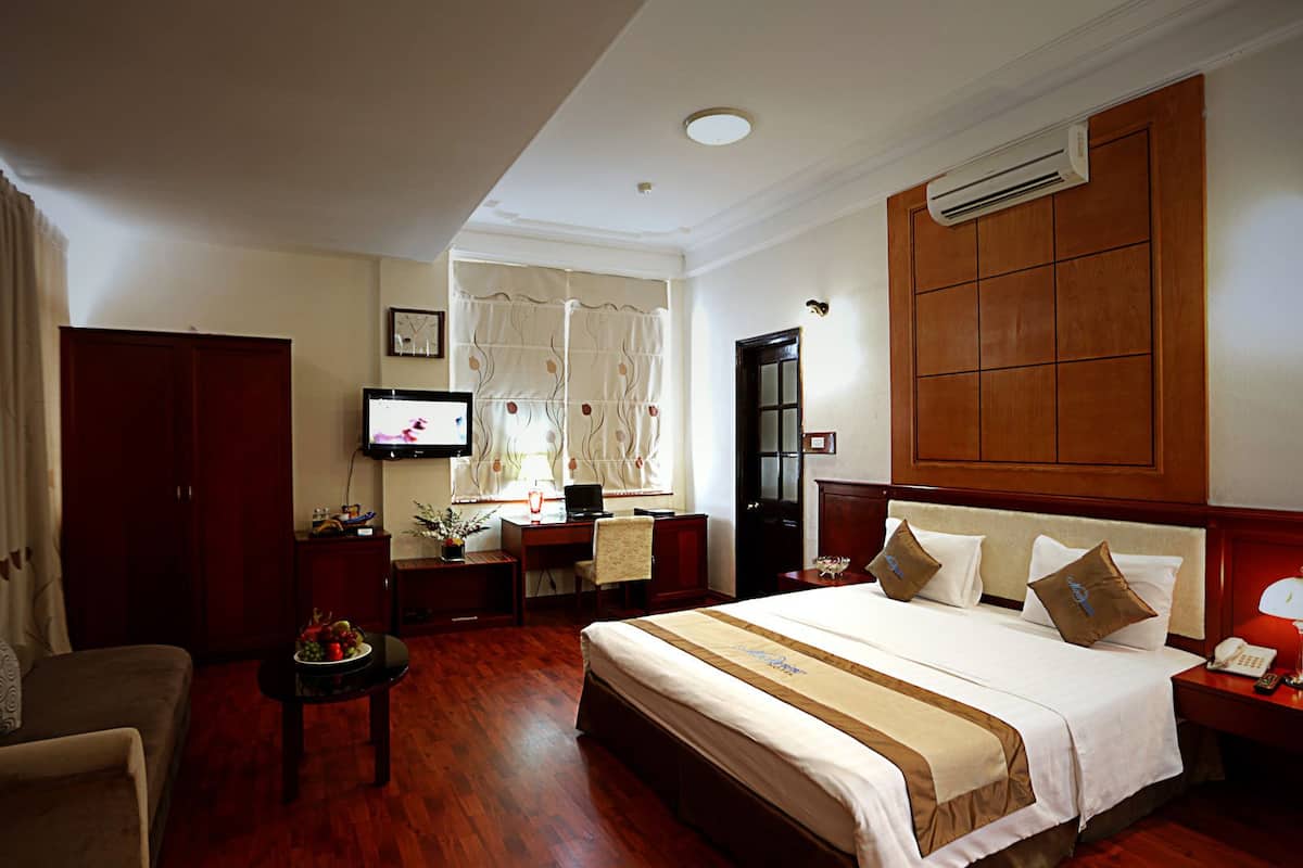 A hotel room with a large bed, a desk, a television, and a wardrobe.