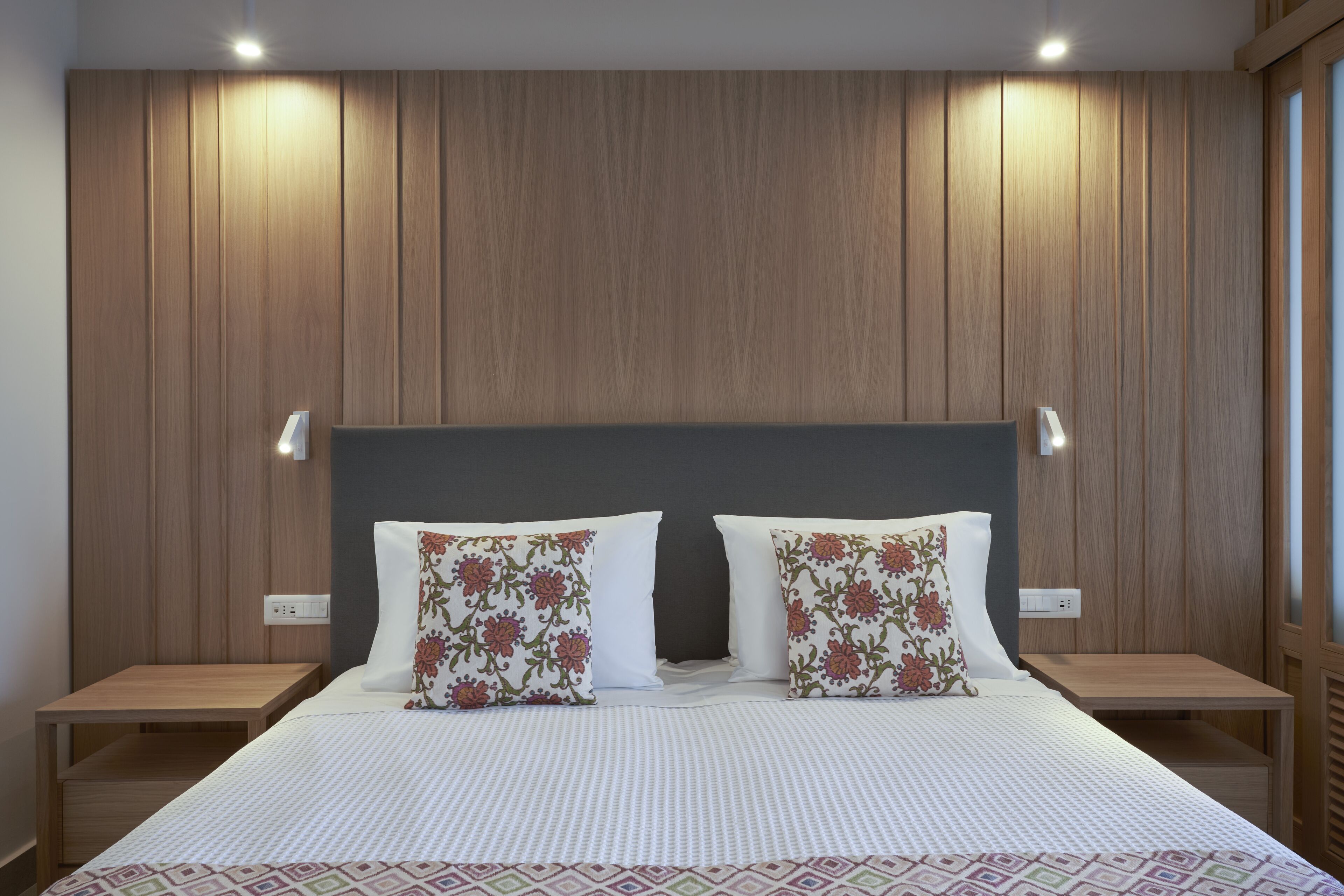 A neatly arranged hotel room with a large bed, two bedside tables, and a wooden panel wall.