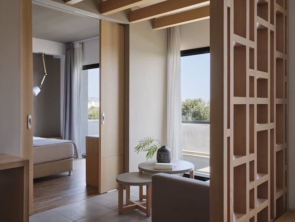 Un dormitori modern amb un llit, una taula rodona petita amb una planta i vista a l'exterior.