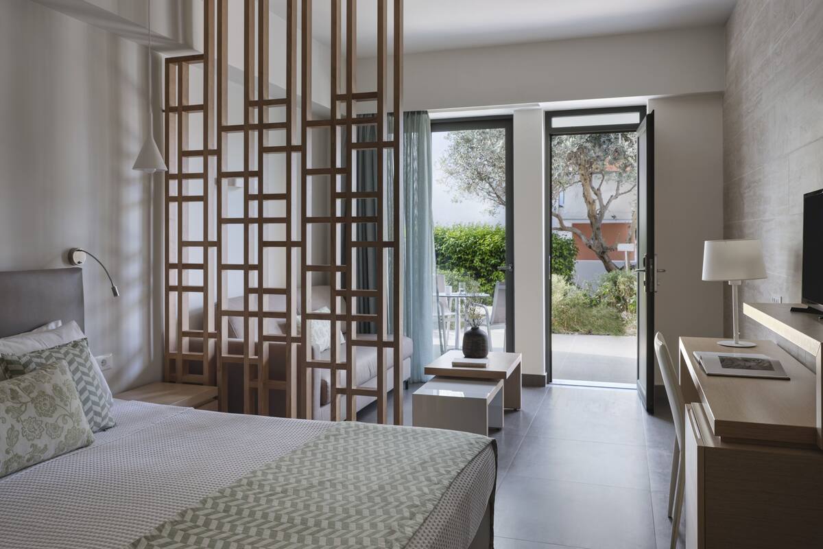 Une chambre d’hôtel moderne dotée d’un grand lit, d’un bureau, d’une télévision et d’un balcon offrant une vue sur l’extérieur.