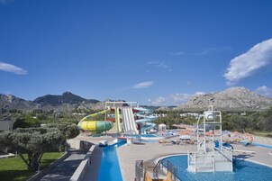 Parque acuático con múltiples toboganes y piscina, rodeado de montañas.