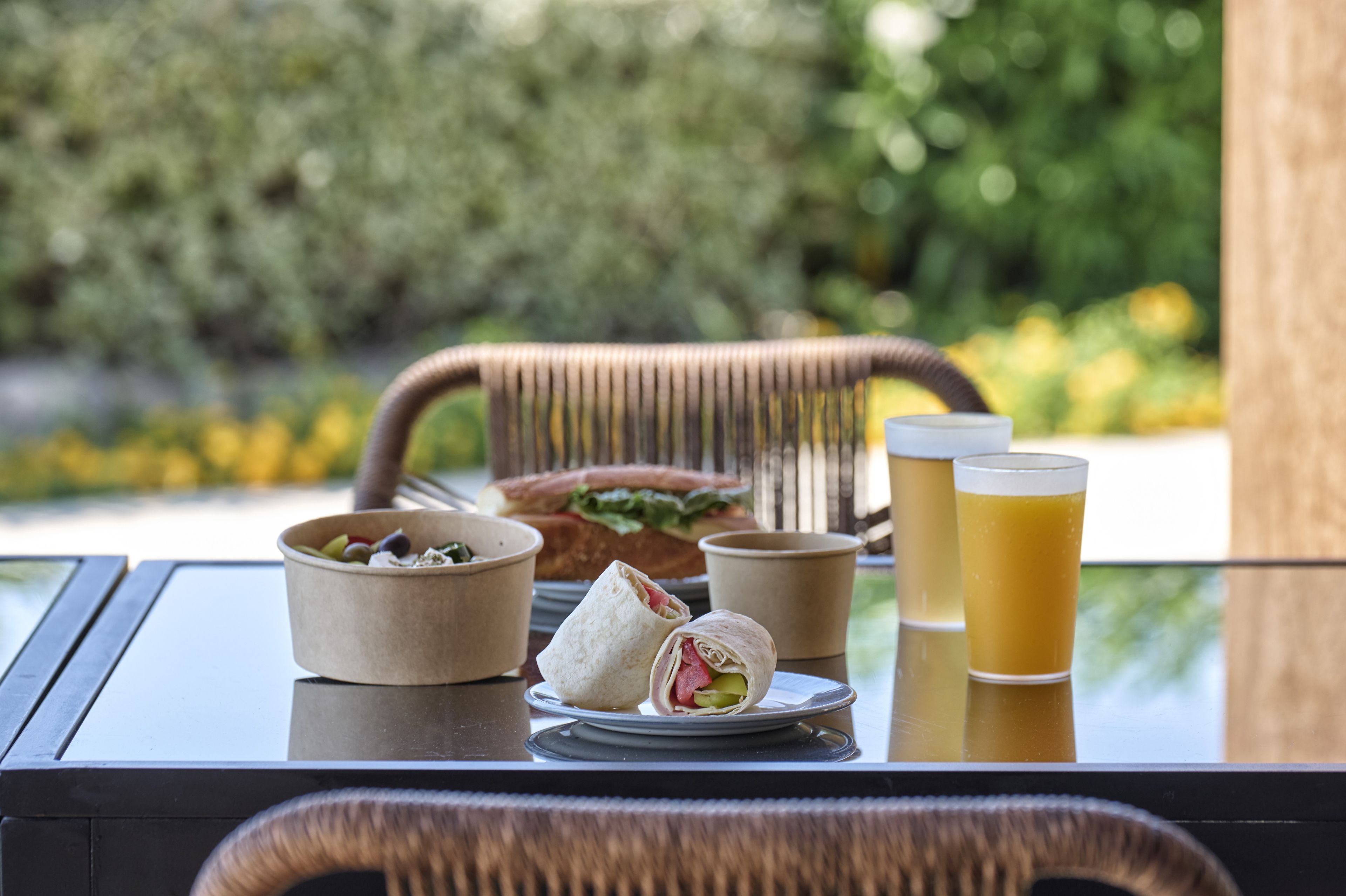 A table with a sandwich, a bowl of olives, a cup of juice, and a glass of beer.