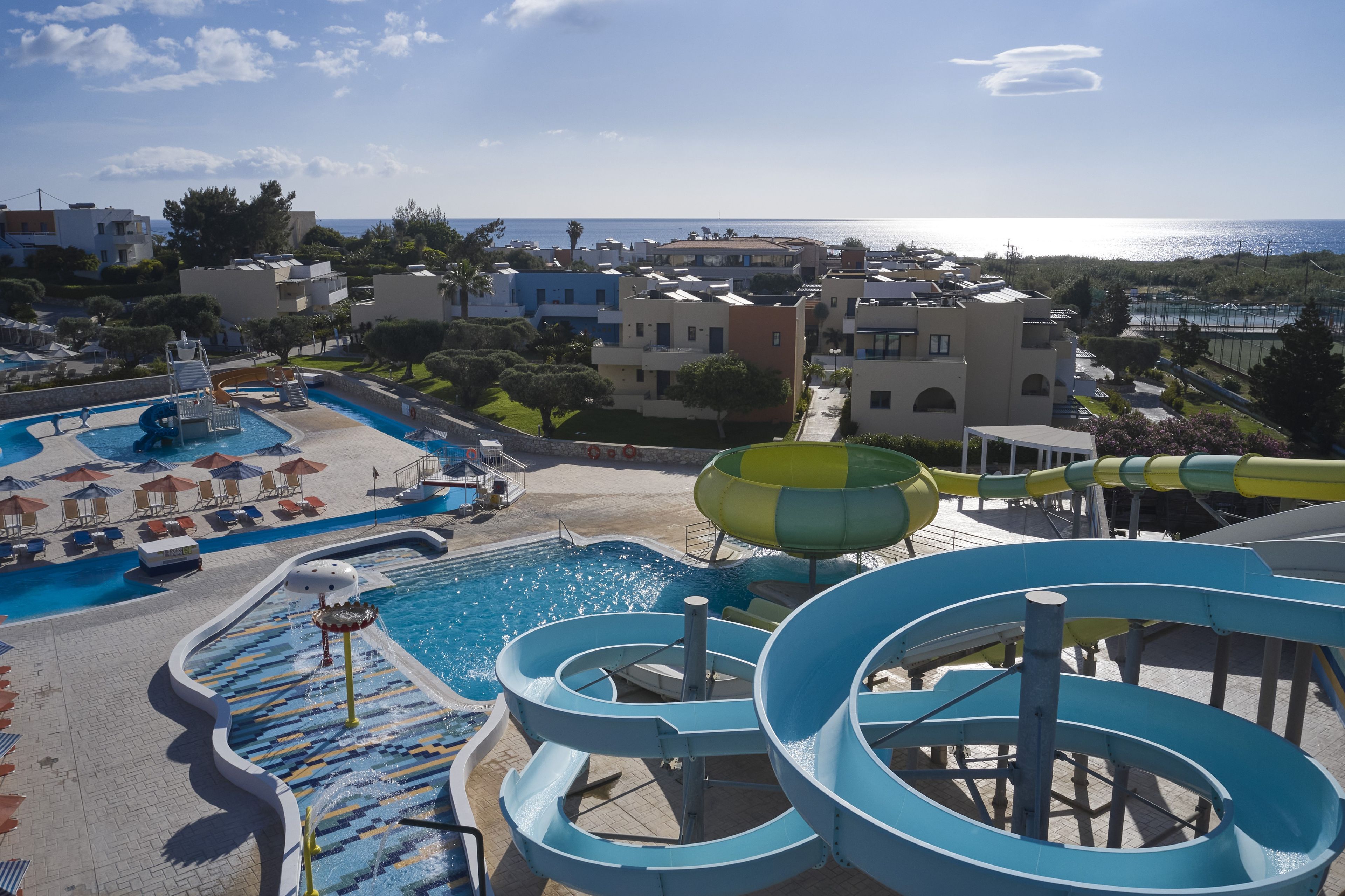 A resort with a pool area, water slides, and a view of the sea.