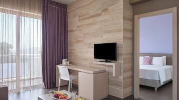 Habitación de hotel moderna con escritorio, televisor, cama y servicio de desayuno que incluye frutas y jugo.