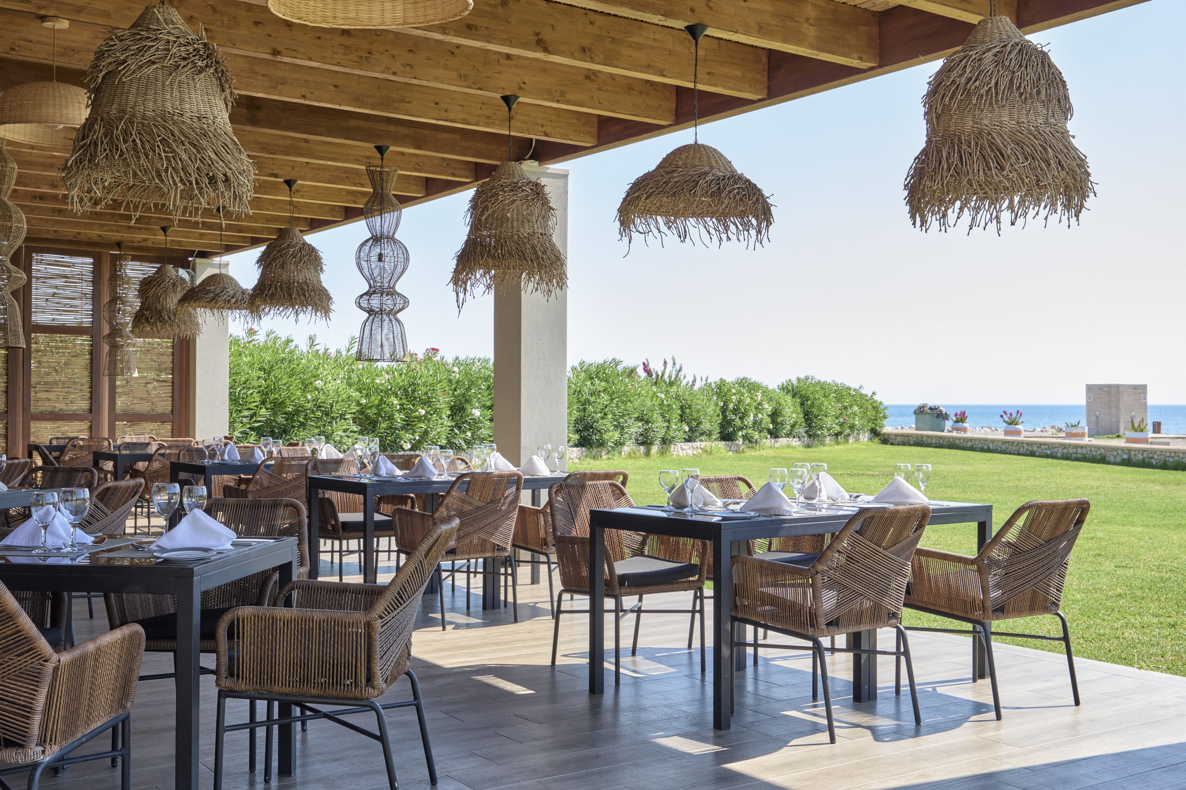 Een terras met rieten meubels en hanglampen.