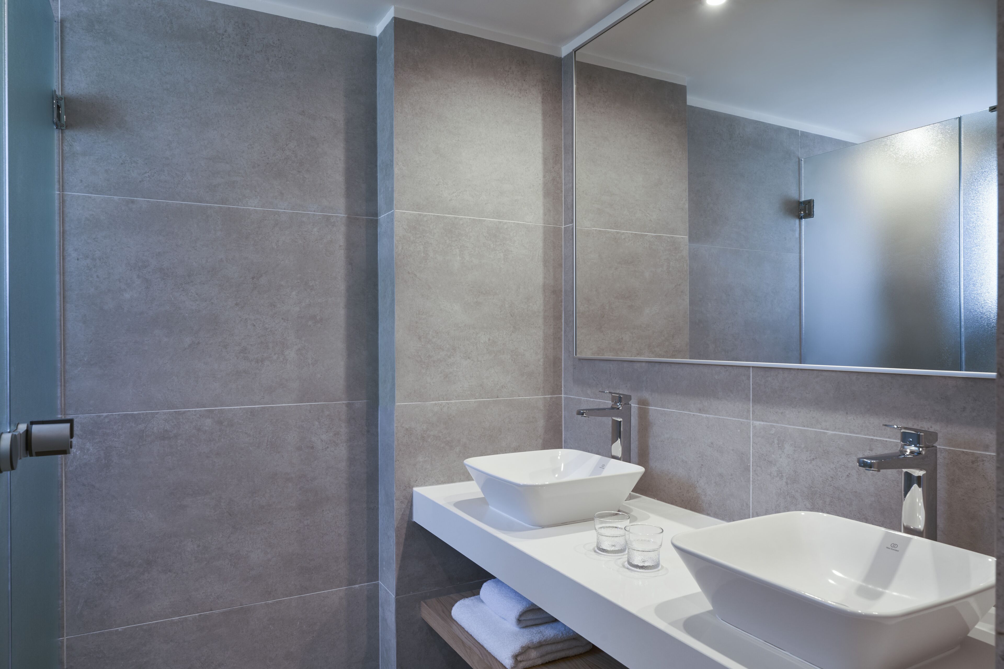 Un baño moderno con dos lavamanos, un espejo y un perchero para toallas.
