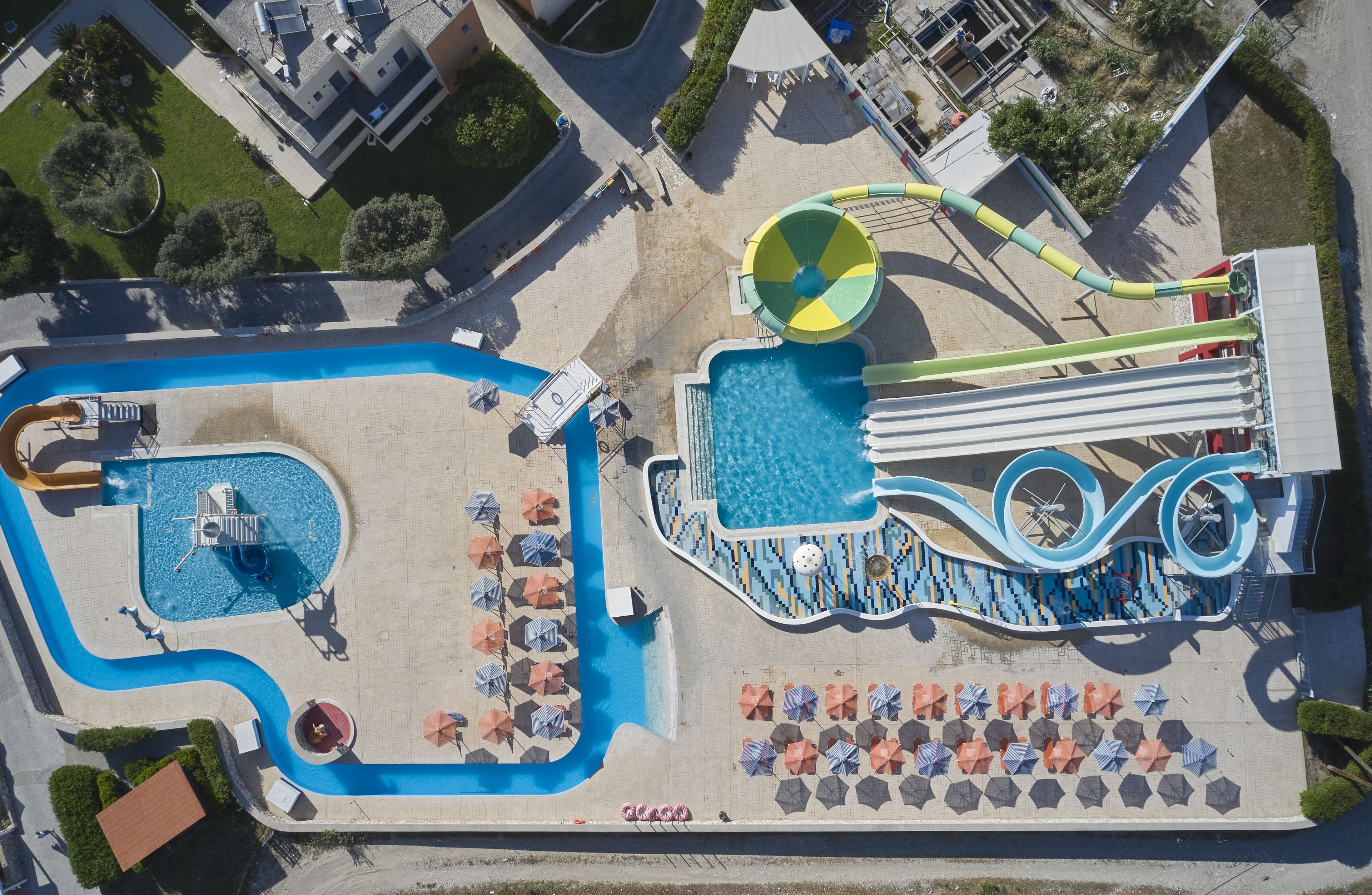 An aerial view of a water park with a swimming pool, slides, and a wave pool.