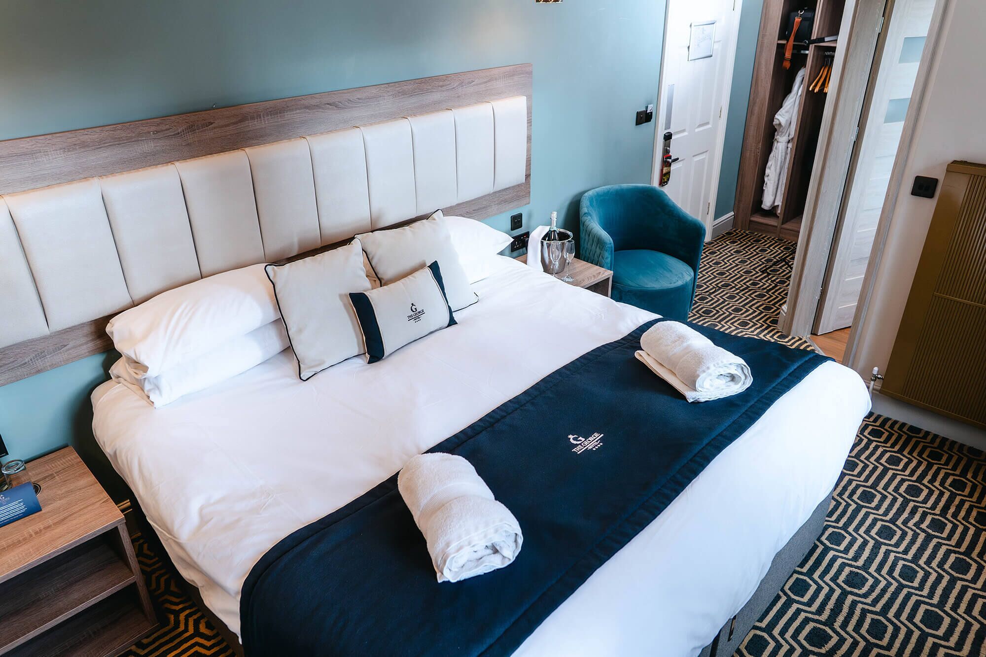 A neatly made bed with a headboard, pillows, and towels.