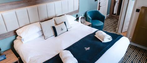 A neatly made bed with a headboard, pillows, and towels.