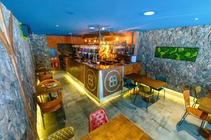 A bar area with a stone wall, wooden tables, and chairs.