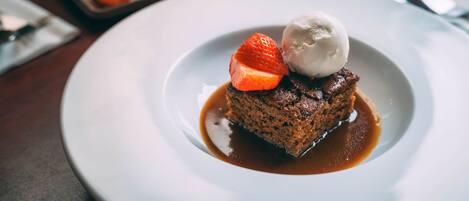 A dessert plate with a chocolate cake, a strawberry, and a scoop of ice cream.