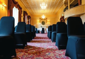 A hotel lobby with rows of blue chairs, a chandelier, and a patterned carpet.
