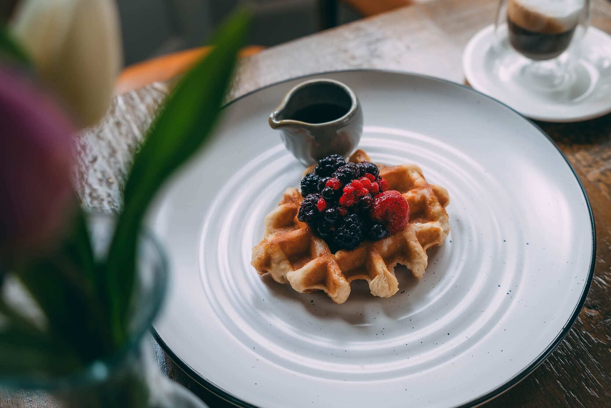 Waffle com frutas vermelhas e calda em um prato.