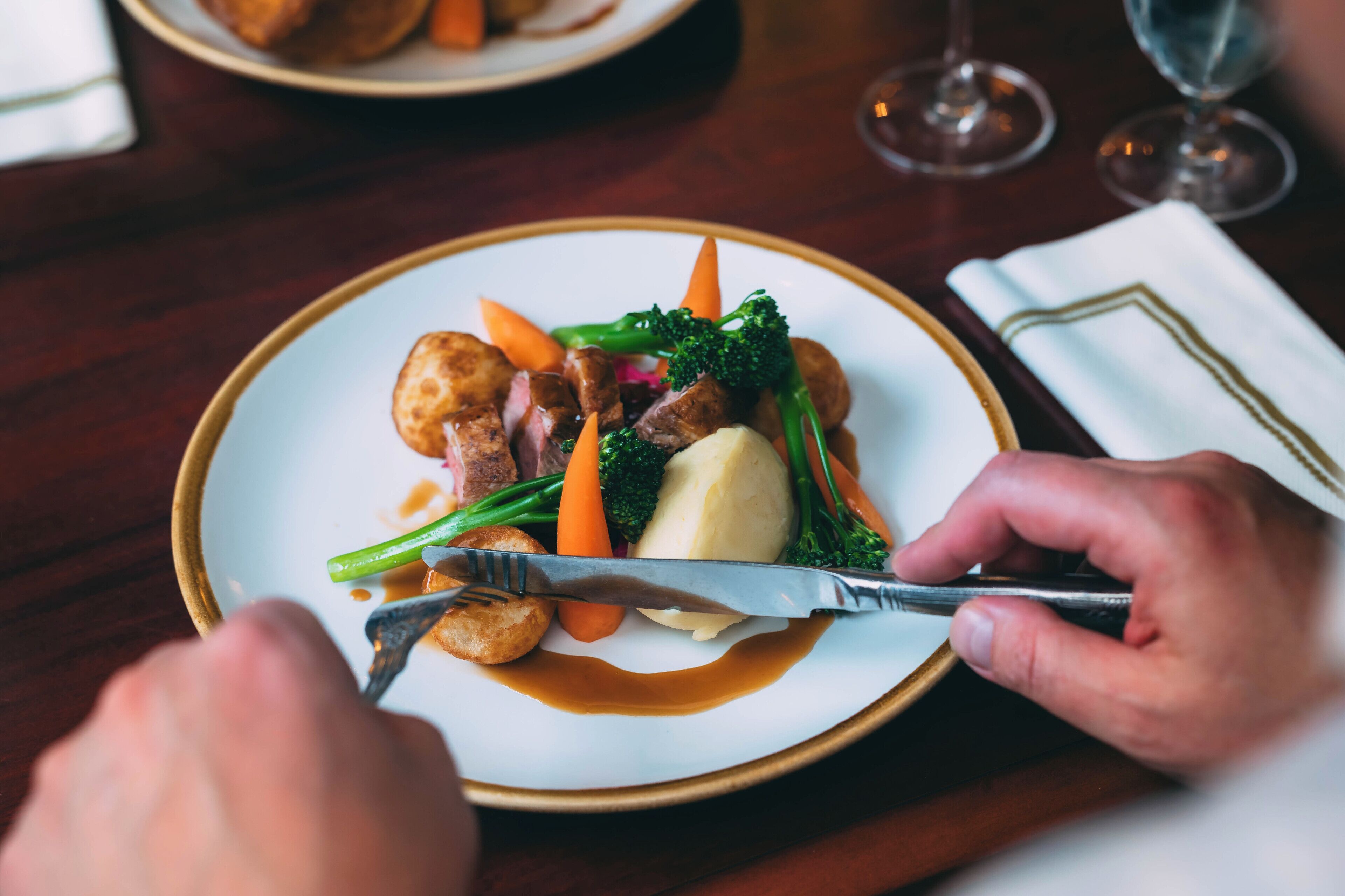 A plate of food with a fork and knife, a glass of wine, and a napkin on a table.