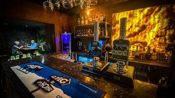 Una zona de bar con mostrador, diversas botellas y un cartel que dice 'CIDER TO SNOUT ABOUT'.