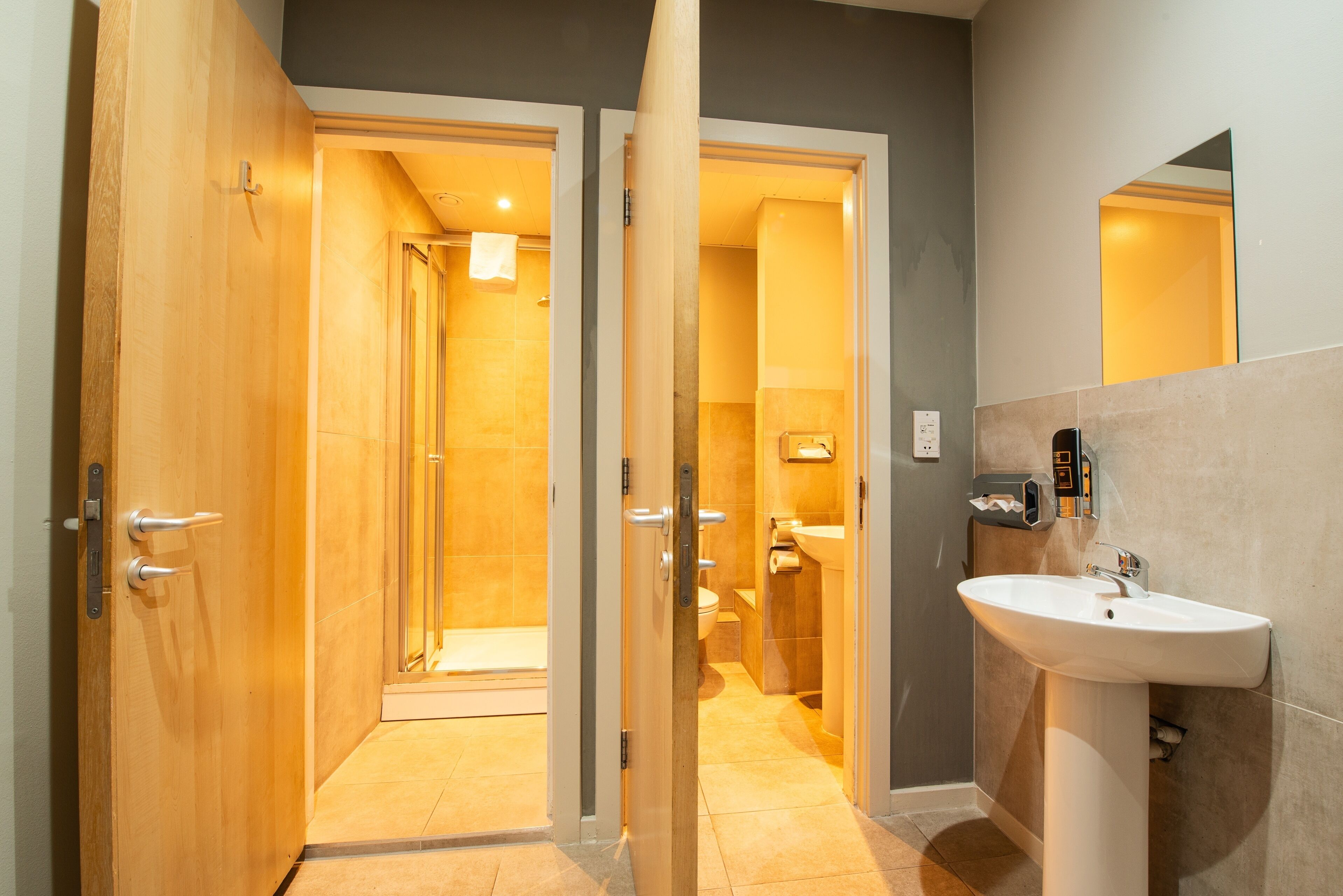 Ein modernes Badezimmer mit Waschbecken, Spiegel und Duschbereich.