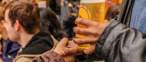 A person holding a glass of beer, with another person reaching out to take it.